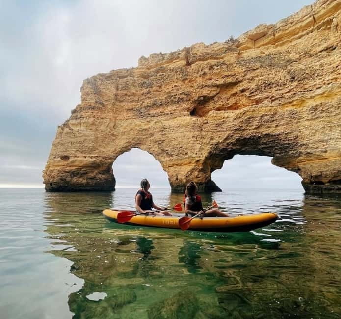 Kayakers passing under a limestone sea arch on the Algarve coast